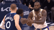 a basketball player with the number 0 on his jersey is shaking hands with another player