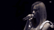 a woman is singing into a microphone on a stage in a dark room .