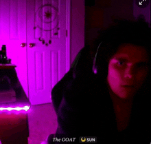 a person wearing headphones in a dark room with the goat and sun written on the bottom