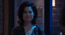 a woman is smiling in a dark room with a brick wall behind her .