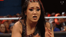 a woman is sitting in a wrestling ring making a funny face .