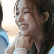 a close up of a woman 's face smiling with her hand on her chin