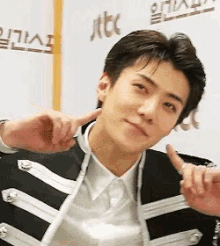 a young man in a black and white jacket giving a thumbs up