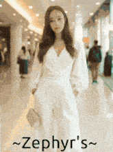 a woman in a white jumpsuit is standing in a hallway with the name zephyr 's written below her