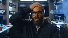 a man with glasses and a beard is holding his head