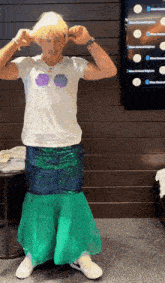 a man wearing a white shirt with seashells and a green skirt