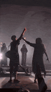 two people are dancing on a stage in a dark room .