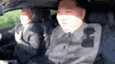 a man in a suit is sitting in the back seat of a car with another man .