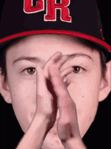 a young boy wearing a cr hat covering his face