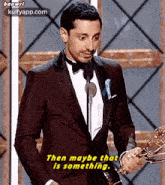 a man in a suit and bow tie is holding a trophy and speaking into a microphone .