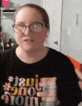 a woman wearing glasses and a black t-shirt that says " i am a mom "