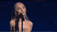 a blonde woman singing into a microphone with a ponytail