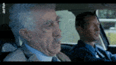 two men are sitting in a car with arte written on the bottom right