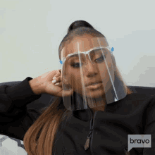 a woman wearing a face shield with a bravo logo on the bottom