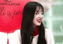 a woman is smiling in front of a red balloon that says open gratulations