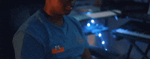 a man wearing a blue shirt with the letter m on the front