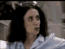 a woman wearing glasses and a blue shirt is sitting on a couch .