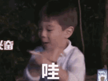 a young boy is making a funny face with his hands while sitting on a bench .