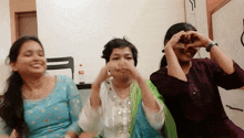 three women are making a heart with their hands in front of their faces