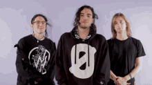 three young men are posing for a picture and one of them is wearing a black hoodie with the letter e on it