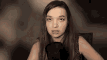 a young woman is sitting in front of a microphone making a funny face .
