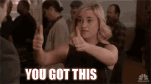 a woman is giving a thumbs up and the words `` you got this '' are on the screen .
