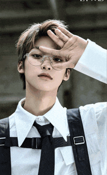 a man wearing glasses and a white shirt holds his hand over his eyes
