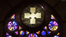 a stained glass window with a white cross in the center
