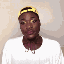 a man wearing a yellow hat and a white shirt is making a funny face .