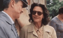a man and a woman wearing sunglasses are standing next to each other and smiling .