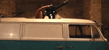 a man is standing on top of a van with a gun on top of it