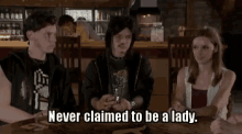 a group of people are sitting at a table and one of them is saying `` never claimed to be a lady `` .