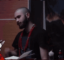 a man with a beard and red beads is holding a piece of paper