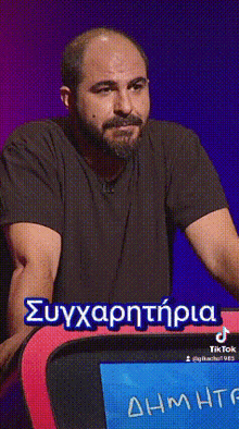 a man with a beard is sitting in front of a screen with the name dimitri written in blue