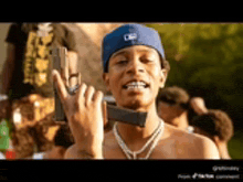 a shirtless man in a blue hat is holding a gun over his shoulder .