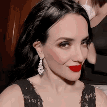 a woman wearing a black dress and red lipstick is smiling .