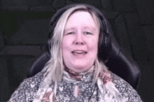 a woman wearing headphones and a scarf is sitting in a chair .