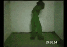 a person in a green suit is standing in a dark room with a time stamp of 19.06.14 .