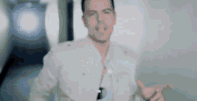 a man in a white jacket is giving a thumbs up while standing in a hallway .