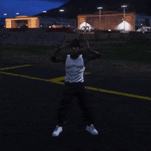 a man in a white tank top is standing in a parking lot giving the middle finger