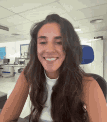 a woman with long brown hair is smiling while sitting at a desk .