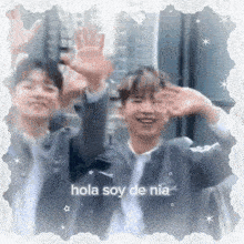 two young men are waving their hands in the air in front of a building in a lace frame .
