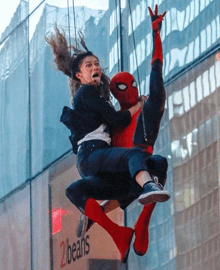 a spider man is holding a woman in his arms in front of a 2beans sign