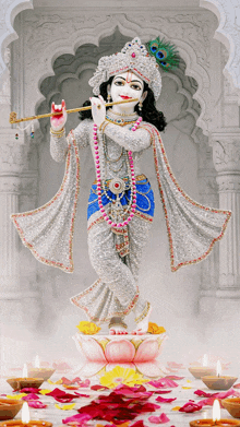 a statue of krishna playing a flute in front of candles