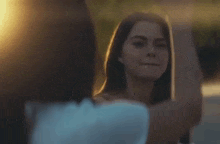 a woman is holding a cell phone in her hand while another woman holds her hands up in the air .