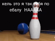 a bowling pin with googly eyes is on a bowling alley next to a bowling ball .