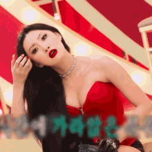 a woman in a red strapless top has red lipstick on her lips and a necklace