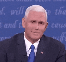 a man in a suit and tie is making a funny face while sitting on a stage .