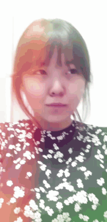 a woman in a black and white floral top looks at the camera