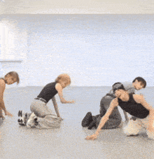 a group of people kneeling on the floor in a dance studio